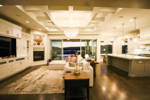 Living room featuring coffered ceiling, dark wood-style flooring, beam ceiling, a glass covered fireplace, and recessed lighting