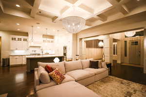 Living room with a chandelier, coffered ceiling, dark wood-type flooring, beamed ceiling, and recessed lighting