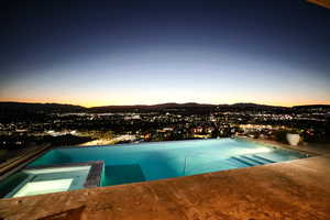 Pool at dusk featuring a pool with connected hot tub and a mountain view