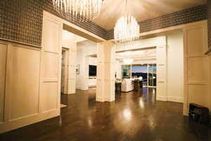 Unfurnished dining area featuring wallpapered walls, dark wood-style flooring, and a chandelier