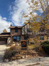 View of front of house with a chimney, an attached garage, and driveway