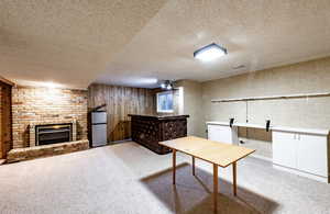 Carpeted home office with a fireplace, a textured ceiling, and wooden walls