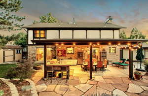Rear view of house with a shed, a patio area, a chimney, and brick siding