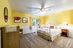 Bedroom with wainscoting, ceiling fan, and carpet