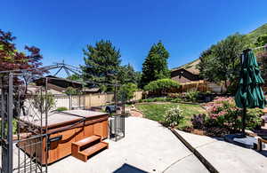 Fenced backyard with a hot tub and a patio
