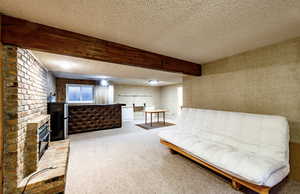 Sitting room with beamed ceiling, carpet flooring, a textured ceiling, and a brick fireplace