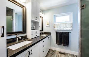 Full bath with light wood finished floors and double vanity
