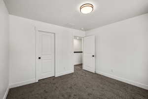 Unfurnished bedroom with dark carpet and a textured ceiling