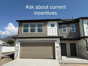 View of front of property with stone siding, concrete driveway, and an attached garage