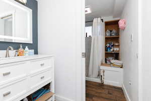 Full bathroom with vanity, dark wood-style floors, and a shower with curtain