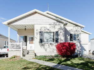 View of front of house with a front lawn, a porch, and stucco siding