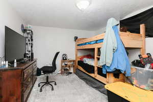 Bedroom 3 featuring a textured ceiling, light carpet, and an office area