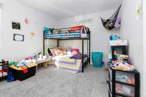 Bedroom 1 featuring light colored carpet and a textured ceiling