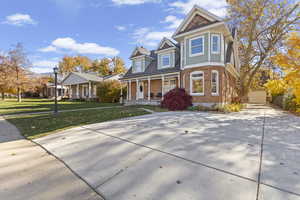 View of front facade with covered porch, brick siding, and a front lawn