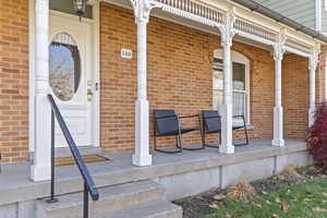 Property entrance featuring brick siding and covered porch