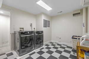 Laundry area featuring tile patterned floors, electric panel, and washer and dryer