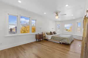 Bedroom with light wood-type flooring, multiple windows, recessed lighting, and a ceiling fan