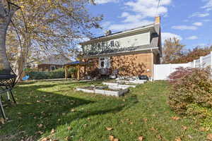 Rear view of property featuring a chimney, brick siding, a vegetable garden, and a gazebo