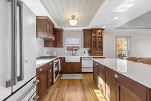 Kitchen featuring high end white refrigerator, decorative backsplash, light wood-type flooring, glass insert cabinets, and double oven range