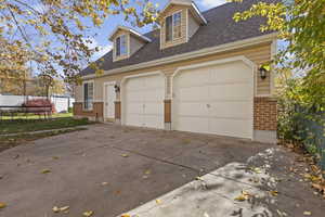 View of property exterior featuring brick siding, roof with shingles, and concrete driveway