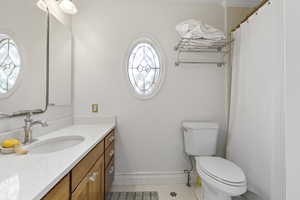 Full bath with light tile patterned floors, vanity, and curtained shower