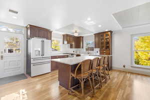 Kitchen featuring a kitchen breakfast bar, high end fridge, backsplash, light wood finished floors, and a center island
