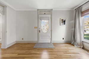 Foyer featuring light wood-type flooring and crown molding