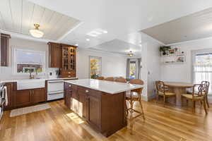 Kitchen featuring plenty of natural light, a breakfast bar area, light wood-style floors, and crown molding