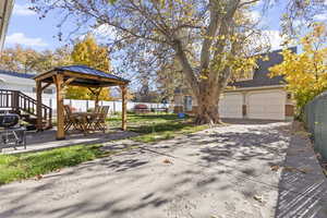 View of yard featuring a gazebo, a garage, a patio, and concrete driveway