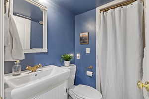 Full bathroom with curtained shower and vanity