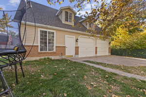 View of front of home with a shingled roof, brick siding, concrete driveway, and an attached garage