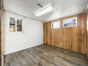 Spare room featuring wood walls and dark wood-type flooring