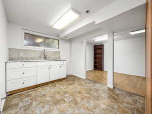 Bar featuring white cabinets, a textured ceiling, and light stone counters