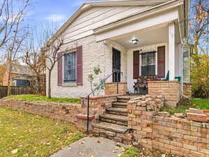 View of exterior entry featuring a porch and brick siding