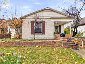 View of front facade with covered porch, a front yard, and brick siding