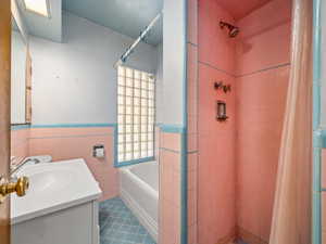 Bathroom with tile walls, vanity, a shower stall, wainscoting, and a bathtub
