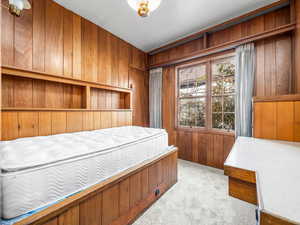 Bedroom with wooden walls and light carpet