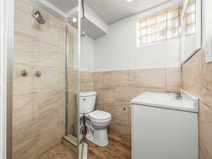 Bathroom with vanity, a stall shower, and tile walls