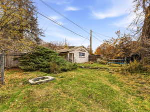 Fenced backyard featuring a trampoline and an outbuilding