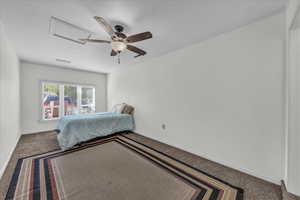 Carpeted bedroom with attic access and ceiling fan