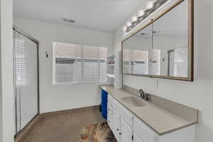 Full bath featuring vanity, a stall shower, and dark tile patterned floors