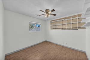 Empty room with wood finished floors, a textured ceiling, and ceiling fan