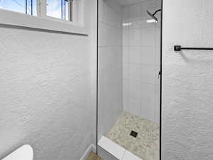 Full bathroom with a textured wall and a stall shower