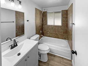 Full bath with a textured wall, vanity, shower / washtub combination, and dark wood-style flooring