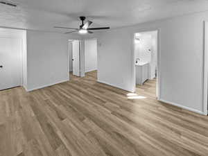 Unfurnished bedroom featuring light wood-style floors, a textured ceiling, and a ceiling fan