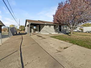 Rear view of property with a lawn, driveway, and roof with shingles