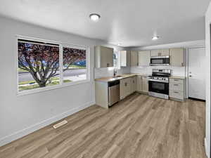Kitchen featuring appliances with stainless steel finishes, light countertops, backsplash, and light wood-type flooring