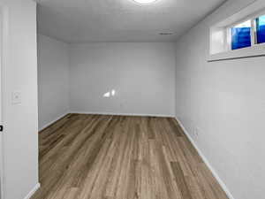 Unfurnished room featuring wood finished floors and a textured ceiling
