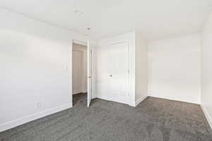 Unfurnished bedroom featuring dark carpet and baseboards
