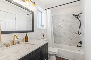 Full bath with shower / bath combo with shower curtain, vanity, and dark wood-style floors